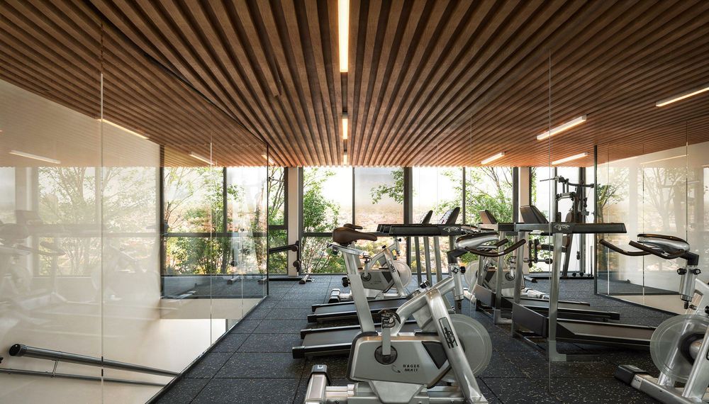 Gimnasio con ventanales de piso a techo y vista a la ciudad
